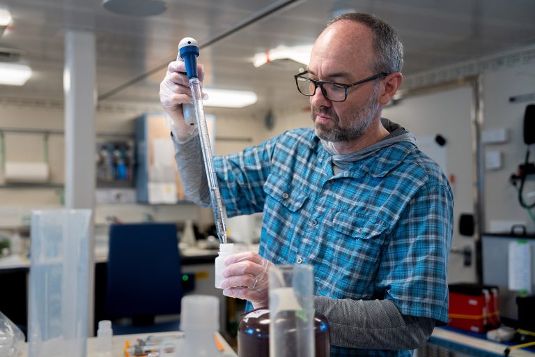 Matthew Church (Chief Scientist and Professor at University of Montana) pipets water samples in the main lab aboard R/V Falkor (too), part of an experiment researching plankton and organic carbon.